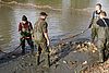 Männer mit Wathosen im Wasser stehend halten ein Netz mit Fischen darin