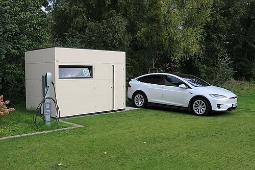 Ein moderner Fahrradschuppen mit Ladestation für Elektroautos und einem Tesla.