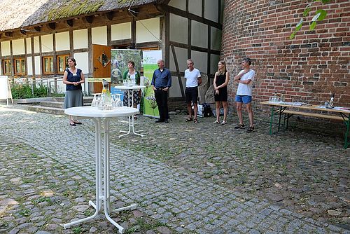 Menschen stehen bei der Eröffnung nebeneinander