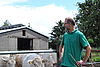 Riccardo Fischer schaut zufrieden über die Schulter. Hinter ihm stehen junge Kühe auf  einer Weide.