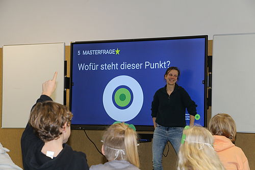 Kinder melden sich um Quizfragen zu beantworten, im Hintergrund wird ein Quiz gezeigt