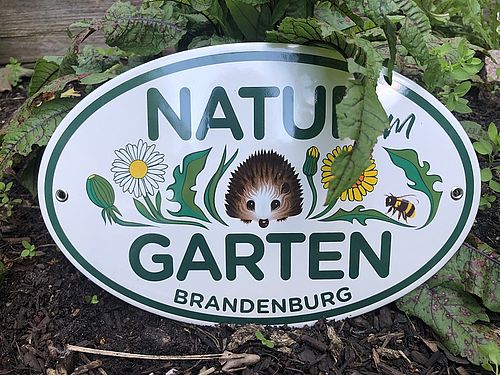 Plakette mit Aufschrift Natur Garten Brandenburg und einem Igel zwischen Wiesenblumen