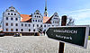 Blick zum Doberluger Schloss. Im Vordergrund steht ein Wanderwegweiser mit der Aufschrift "erlebnisREICH Naturpark "