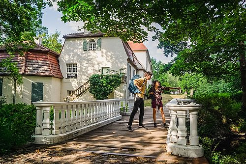 Zwei Wanderer auf der Brücke im Schlosspark Blankensee. Im Hintergrund das Schloss.