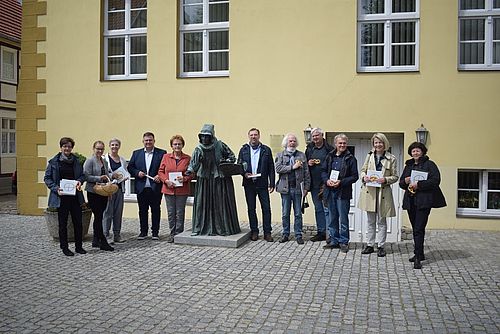 Die Teilnehmenden der Reise stehen neben der Anna Grieben Skulptur vor dem Lenzener Rathaus. 