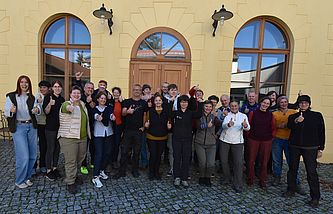 Eine Gruppe von Menschen steht vor einem Gebäude für ein Gruppenportrait.