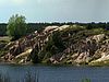 Ein Seeufer: die steilen Sandflächen sind kaum bewachsen und von tiefen Rinnen durchzogen.