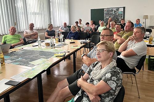 Menschen sitzen in einem Raum und schauen interessiert